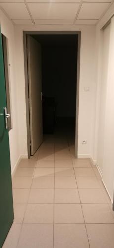un couloir vide avec une porte noire et du carrelage dans l'établissement Studio, à Avignon