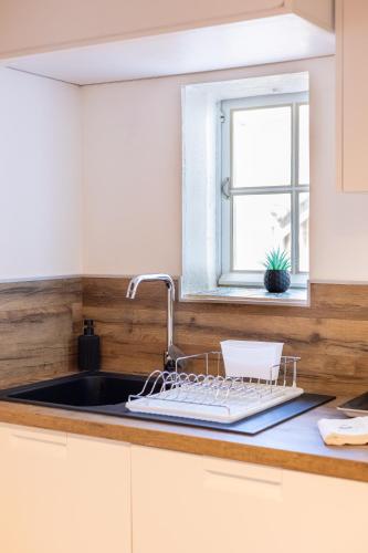 - un évier de cuisine avec un étendoir à vaisselle à côté d'une fenêtre dans l'établissement Escapade au cœur de Sanary, à Sanary-sur-Mer