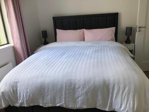 a bedroom with a white bed with pink pillows at Bungalow in the countryside in Roscommon