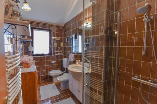 a bathroom with brown tiled walls and a sink and a toilet at Casa Andrea in Mošćenička Draga