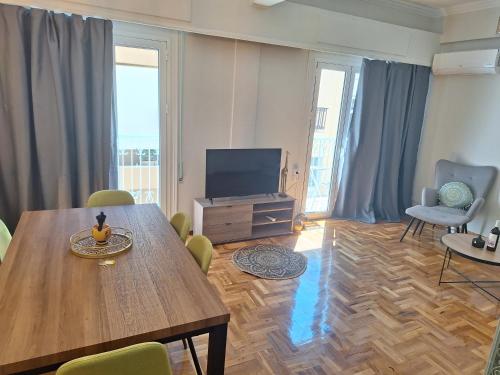 un soggiorno con tavolo in legno e TV di Caryatids luxury apartment ad Atene