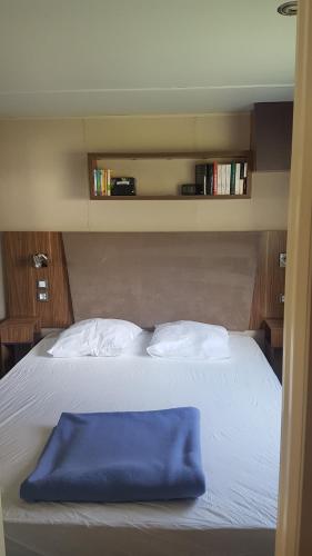 Una cama con una manta azul encima. en Mobil-home 3ch, 2 sdbwc, tout confort camping les allais Trogues, en Trogues