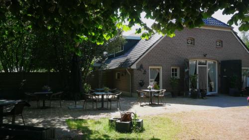 Bij Aquamarijn في Stieltjeskanaal: منزل به طاولات وكراسي في الفناء