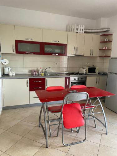 uma cozinha com uma mesa vermelha e cadeiras vermelhas em Sunrise Apartment em Pogradec