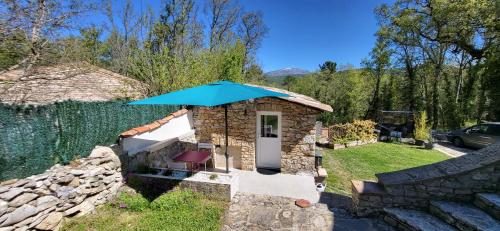 una pequeña casa de piedra con una sombrilla azul en Les Pierres de Cézaire en Saint-Cézaire-sur-Siagne