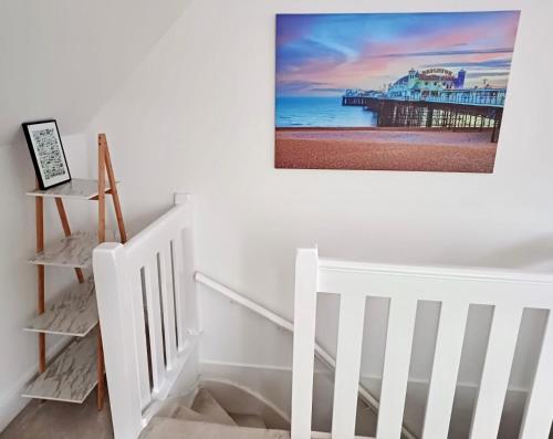 a white staircase with a picture of a pier on the wall at Modern maisonette in Hove free parking dog friendly in Brighton & Hove