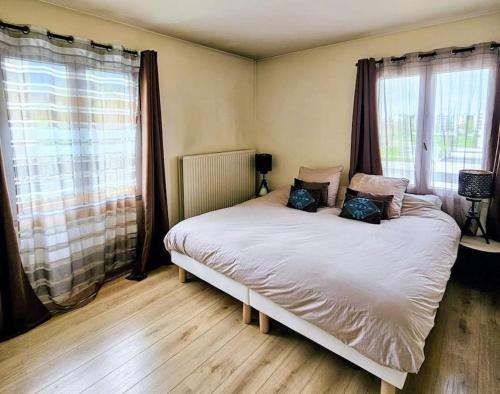 una cama en una habitación con dos ventanas en Appartement spacieux silencieux, en Lognes
