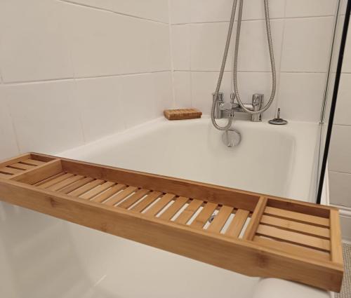 a bath tub with a wooden frame in a bathroom at Modern maisonette in Hove free parking dog friendly in Brighton & Hove