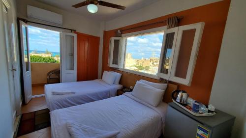 two beds in a room with two windows at Adriatica Hotel Marsa Matrouh in Marsa Matruh