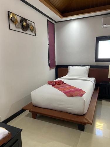 a bedroom with a bed with white sheets and a window at Lris villas in Phuket Town