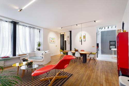 un salon avec une chaise rouge et une table dans l'établissement Luxueux LOFT 3BR au coeur du Marais, à Paris