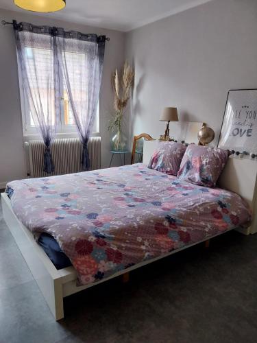 a bedroom with a bed with a colorful quilt on it at Les Hirondelles du MAMBOURG in Sigolsheim