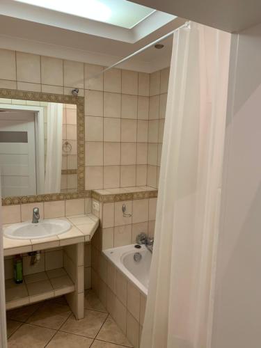 uma casa de banho com um lavatório, uma banheira e uma cortina de chuveiro em Apartament Wyszyńskiego 32m16 em Kalisz