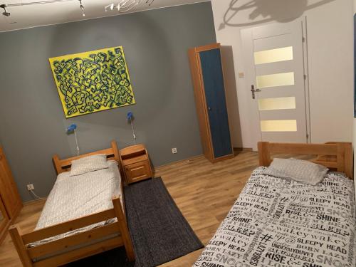 um quarto com duas camas e um quadro na parede em Apartament Wyszyńskiego 32m16 em Kalisz