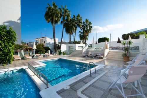 - une piscine entourée de chaises et de palmiers dans une maison dans l'établissement Hotel Tarba, à Sant Antoni de Portmany