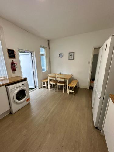 a kitchen with a table and a washing machine at Quirky Oasis Anfield in Liverpool