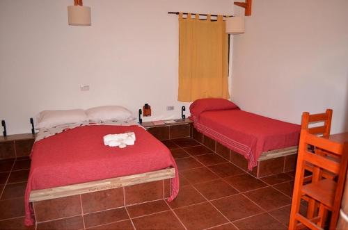 a room with two beds with red covers and a window at Cabañas en La Gloria in Villa Elisa