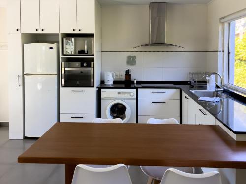 a kitchen with a wooden table and white appliances at Casa Country Altos Arrayanes in Mercedes
