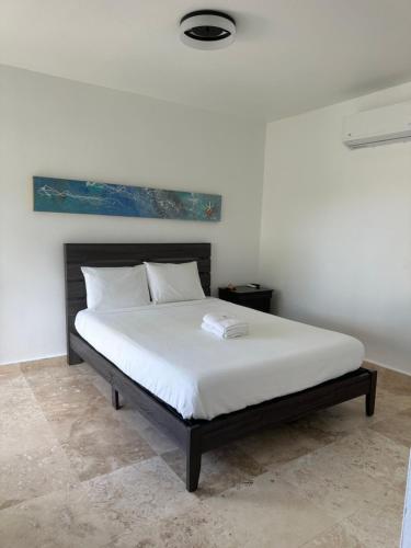 1 dormitorio con 1 cama grande con sábanas blancas en Manati World Point Inn, en Manatí