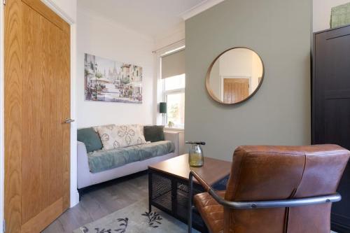 uma sala de estar com um sofá e um espelho em Serene Earlsdon Flat With Smart TV, Wifi & 10 Minute walk to Train Station em Spon End