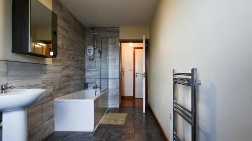 ein Badezimmer mit einem Waschbecken und einer Badewanne in der Unterkunft THROSTLES NEST APARTMENTS in Manchester