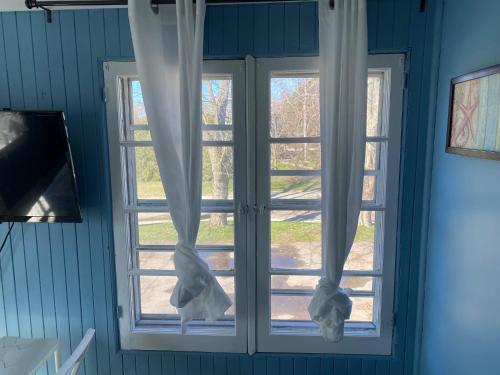 a window with white curtains in a blue room at Windspire Inn in Port Elgin