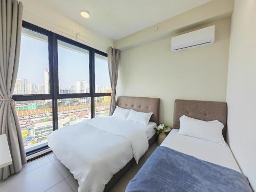 two beds in a room with a large window at Urban Suites Georgetown New Condo City View 158 in Jelutong