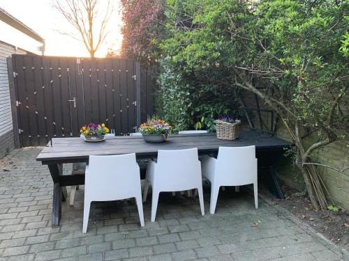 a wooden table with four chairs and flowers on it at Romantisch Wellness Appartement met privé Hottub Sauna Gamesroom in Den Ham
