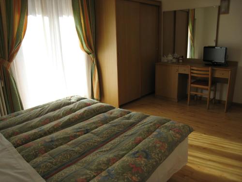 a bedroom with a bed and a desk and a table at Garni B&B Mozart Nesthouse in Canazei