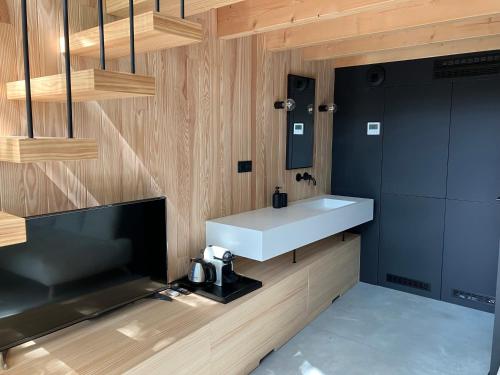 La salle de bains est pourvue d'un lavabo blanc et d'une télévision. dans l'établissement NOUVEAU - Ecolodge calme dans un écrin de verdure - Avec piscine au Golf-Lac de Biscarrosse - Couchage 2 personnes, à Biscarrosse