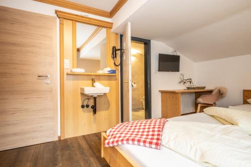 a bedroom with a bed and a bathroom with a sink at Mara's Little Boutique Sleepover - Budget Holiday Home in Kaprun