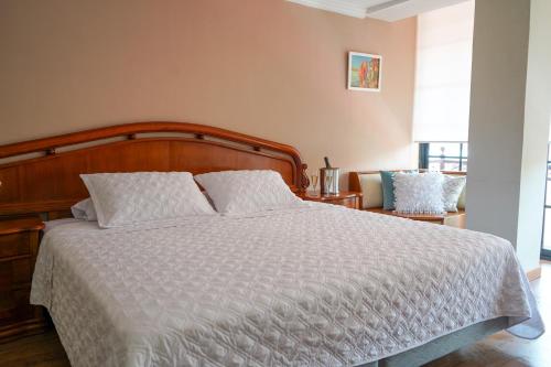 a bedroom with a large bed with a wooden headboard at Grand Hotel Santa Ana in Cuenca