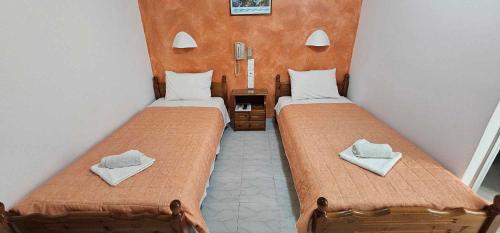 two beds in a small room with towels on them at Hotel Palladion in Karterados
