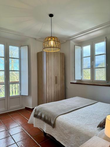 a bedroom with a bed and a chandelier and windows at Apartamentos Santa Marina in Llanes