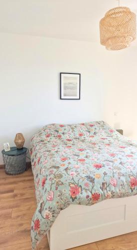 une chambre avec un lit avec un couvre-lit fleuri dans l'établissement Appartement moderne, hyper-centre, 2km des plages, à Fouesnant