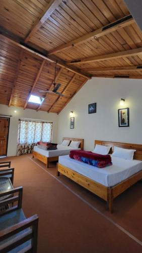 two beds in a large room with wooden ceilings at Oak Essence in Mukteswar