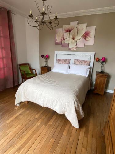 1 dormitorio con 1 cama con sábanas blancas y flores rosas en la pared en Maison de Charme, en Champs-Sur-Marne