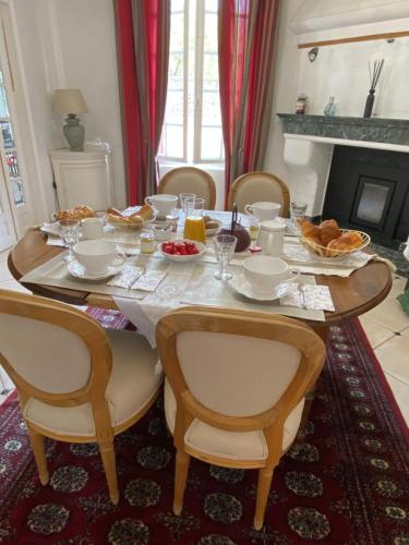 une table de salle à manger avec des chaises et de la nourriture dessus dans l'établissement Maison de Charme, à Champs-sur-Marne