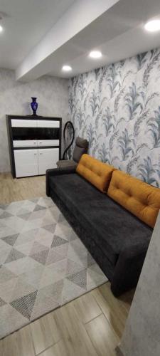 a black couch in a living room with a wall at Butas Siluteje in Šilutė