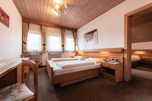 a bedroom with two beds and a wooden ceiling at Hotel Goldene Rose in Monguelfo