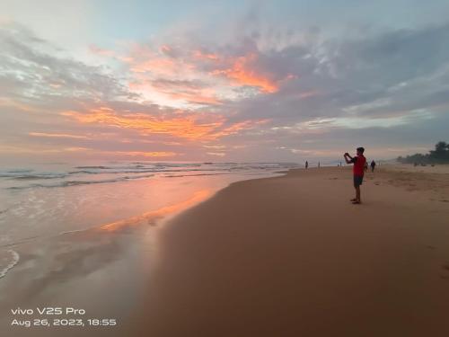 a man walking on the beach at sunset at Farm Stay near Gokarna beach Bhavikodla with AC and Kitchen in Gokarn