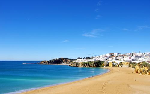 a view of a beach with a town in the background at Ocean view Apartment with 3 spacious Terraces, 2 Swimming pools & Tennis court in Albufeira
