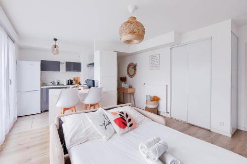 une chambre blanche avec un lit et une cuisine dans l'établissement Charmant 2 pièces avec Terrasse Proche Transport, à Épinay-sur-Seine