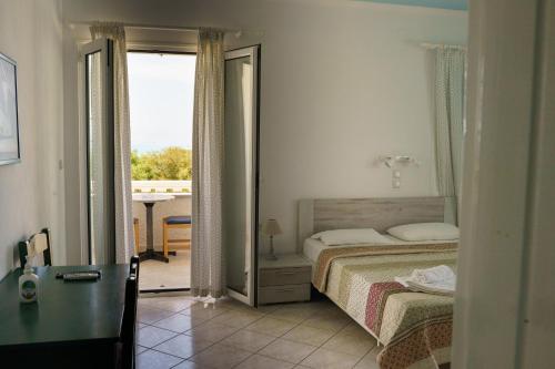 1 dormitorio con cama y vistas a un balcón en Sigma Hotel, en Paralia Vrachou
