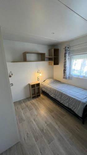 une chambre avec un lit et un parquet dans l'établissement Sbvacances Entièrement équipé et tout confort grand 2ch avec suite parentale et 2 sdb dans camping 4 étoiles, à Saint-Julien-en-Born