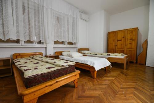 two beds in a room with wooden floors and windows at Banat Terra Biserno Ostrvo in Novi Bečej
