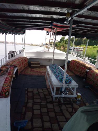 um barco com uma cama e um banco no convés em أسوان em Aswan