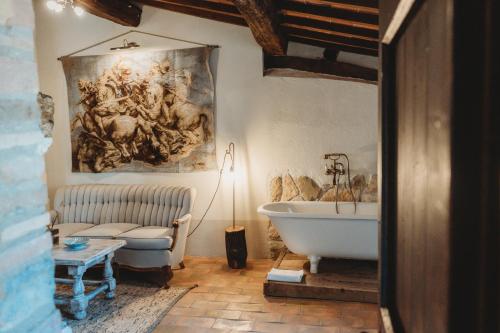 カスティリオーネ・ドルチャにあるLocanda in Tuscanyの壁に絵画が飾られたバスルーム(バスタブ付)