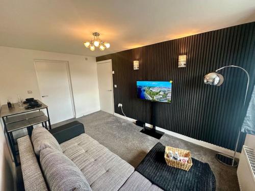 a living room with a couch and a tv on a wall at Your Stylish Totterdown Haven in Bristol
