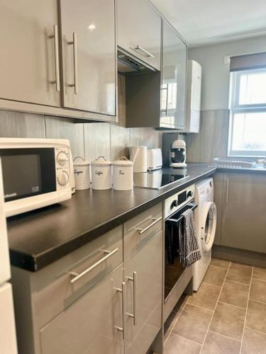 a kitchen with a counter top with a microwave at Your Stylish Totterdown Haven in Bristol